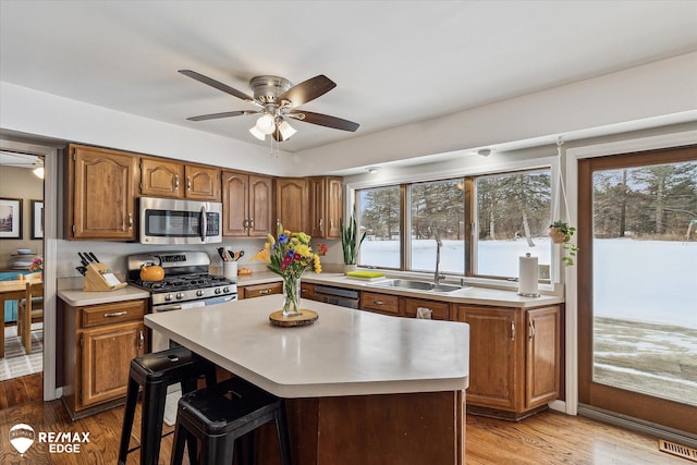 kitchen featuring appliances with stainless steel finishes, sink, a center island, ceiling fan, and light hardwood / wood-style flooring