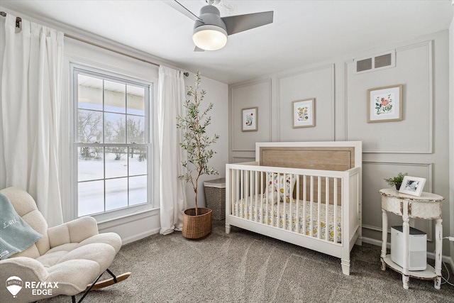 carpeted bedroom featuring a crib and ceiling fan