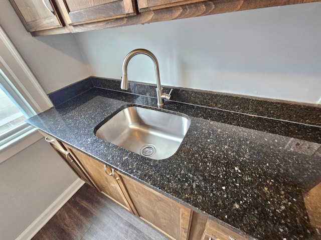 room details featuring dark stone counters, sink, and wood-type flooring