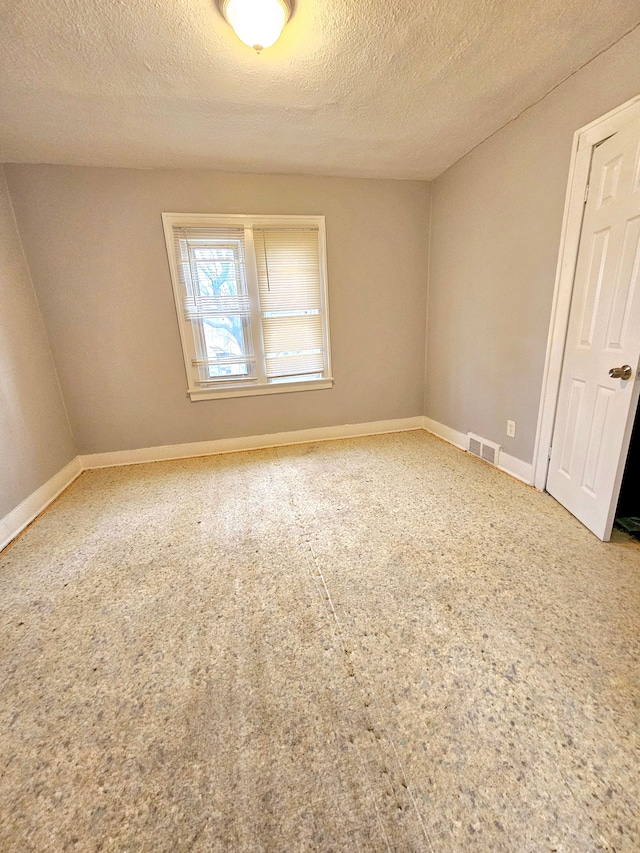 carpeted empty room with a textured ceiling