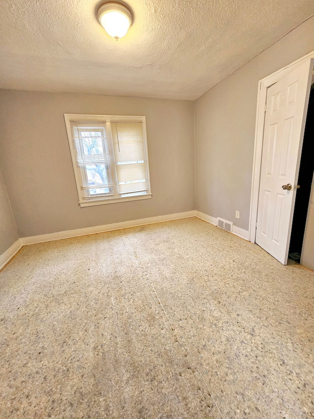 spare room with a textured ceiling and carpet flooring