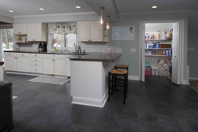 kitchen featuring plenty of natural light, white cabinets, a kitchen bar, and decorative light fixtures