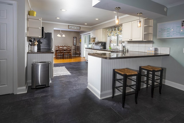 kitchen with pendant lighting, backsplash, white cabinets, a kitchen breakfast bar, and kitchen peninsula