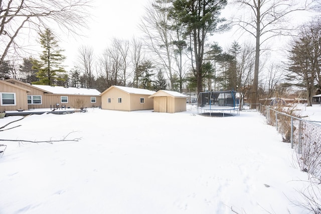 snowy yard featuring a shed and a trampoline