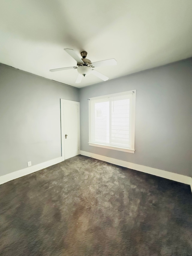 spare room with ceiling fan and dark carpet