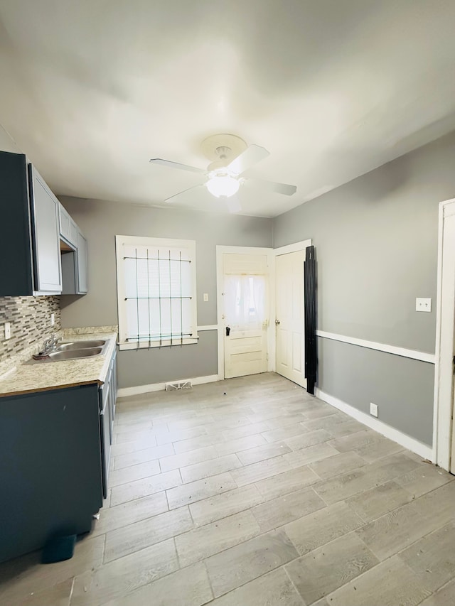 kitchen with tasteful backsplash, sink, ceiling fan, and light hardwood / wood-style flooring