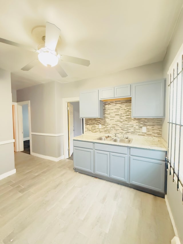 kitchen featuring gray cabinets, sink, decorative backsplash, ceiling fan, and light wood-type flooring