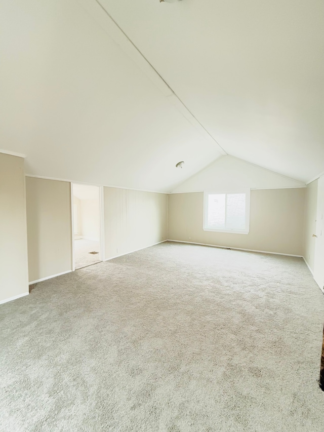 additional living space with vaulted ceiling and carpet flooring