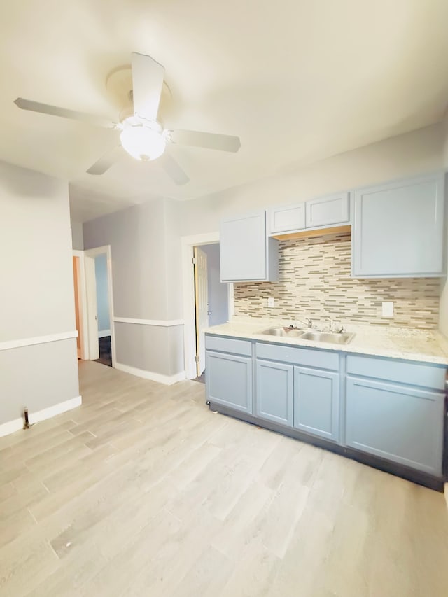 kitchen with ceiling fan, sink, light hardwood / wood-style floors, and decorative backsplash