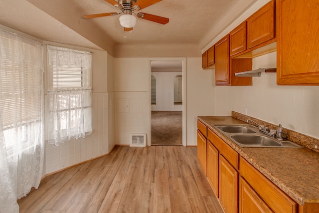 kitchen with ceiling fan, sink, light hardwood / wood-style flooring, and a textured ceiling