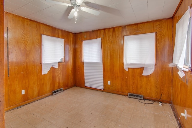 spare room featuring ceiling fan and wood walls