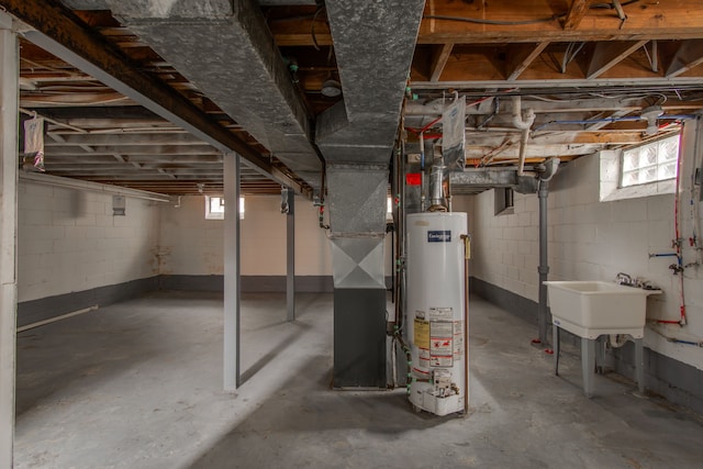 basement featuring heating unit, plenty of natural light, sink, and water heater