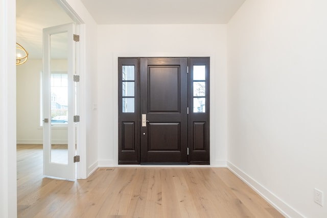 foyer entrance with baseboards and light wood-style floors