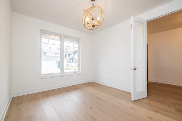 spare room with light wood finished floors, baseboards, visible vents, a chandelier, and lofted ceiling