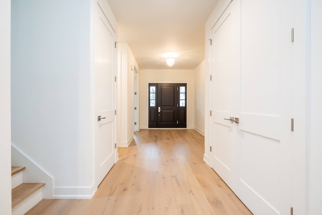 foyer entrance featuring baseboards, stairs, and light wood-type flooring