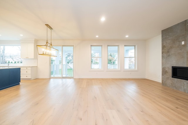 unfurnished living room with light wood-style flooring, baseboards, a tile fireplace, and recessed lighting