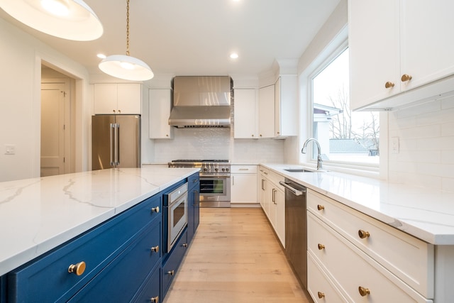 kitchen featuring hanging light fixtures, premium appliances, light stone countertops, blue cabinets, and wall chimney exhaust hood