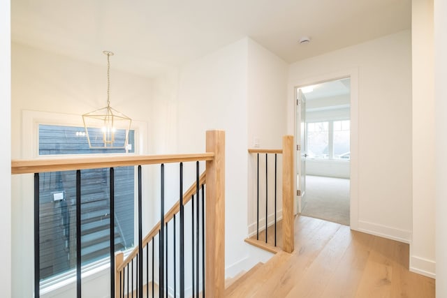 hallway featuring an inviting chandelier, wood finished floors, an upstairs landing, and baseboards