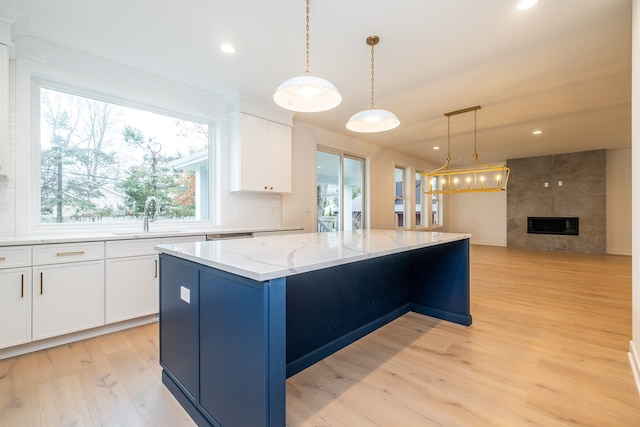 kitchen featuring white cabinets, a center island, a sink, and light wood-style floors