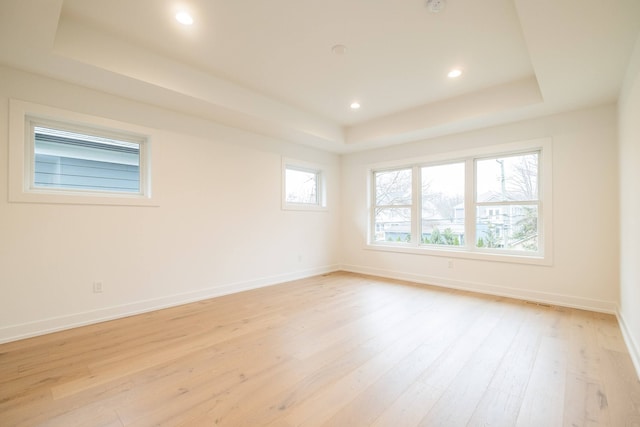 spare room featuring a tray ceiling, light wood-style flooring, baseboards, and recessed lighting
