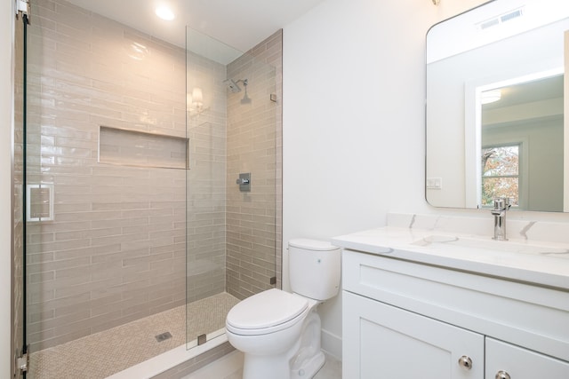 bathroom with visible vents, toilet, tiled shower, and vanity