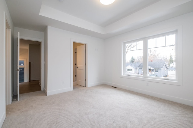 unfurnished bedroom featuring a tray ceiling and light colored carpet