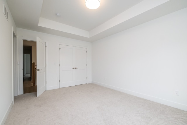 unfurnished bedroom featuring baseboards, visible vents, a closet, and light colored carpet