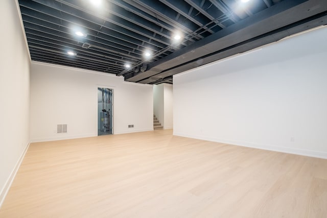finished below grade area with visible vents, baseboards, wood finished floors, and stairs