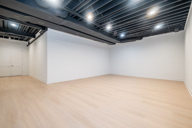 finished basement featuring light wood-style flooring and baseboards