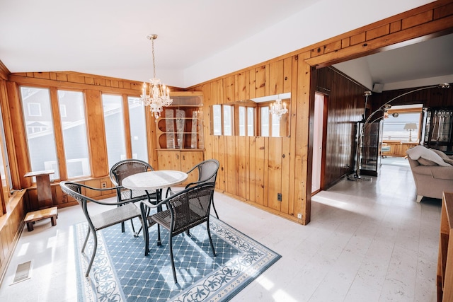 dining area with a chandelier and wooden walls