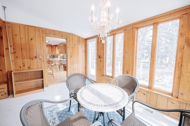 dining room with a notable chandelier and wood walls