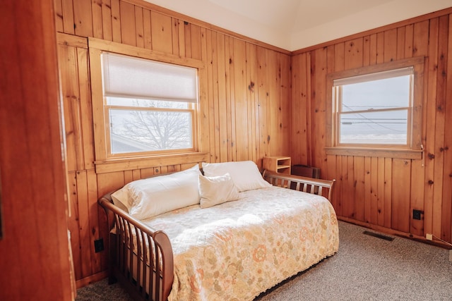 bedroom with lofted ceiling, wooden walls, and carpet