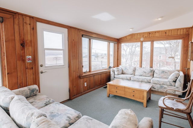 carpeted living room with lofted ceiling, a wealth of natural light, and wooden walls