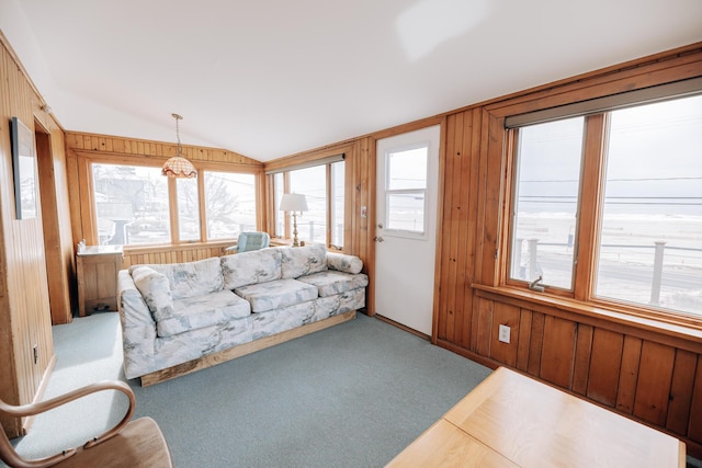 living room featuring lofted ceiling, light carpet, and wood walls