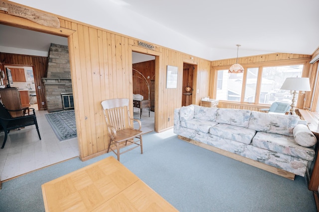 carpeted living room featuring lofted ceiling, a stone fireplace, and wood walls