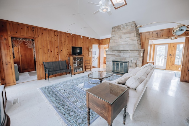 living room featuring ceiling fan, lofted ceiling, a fireplace, and wood walls