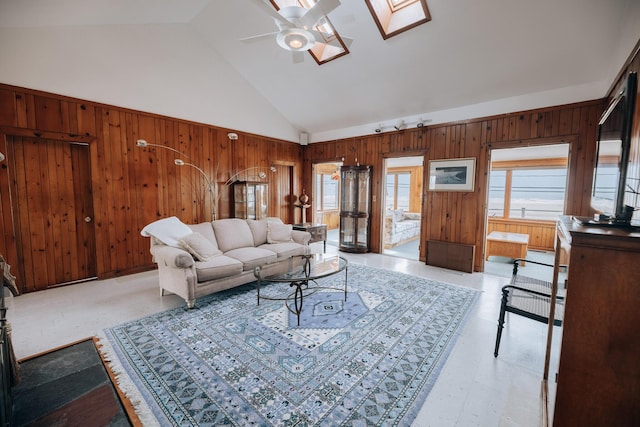 living room with a skylight, high vaulted ceiling, plenty of natural light, and wood walls