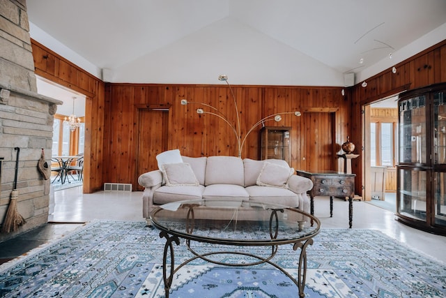 living room featuring a healthy amount of sunlight, high vaulted ceiling, and wood walls