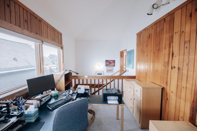 office with lofted ceiling, light carpet, and wood walls