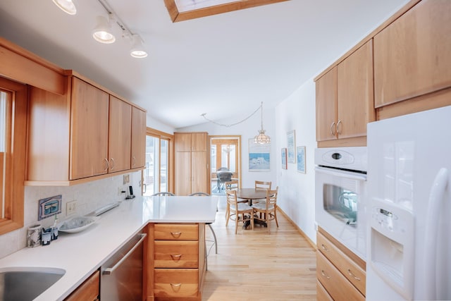 kitchen with hanging light fixtures, light wood-type flooring, light brown cabinetry, and white appliances