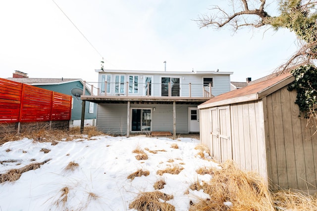 snow covered property with a shed and a wooden deck