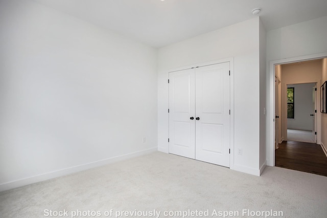 unfurnished bedroom featuring light colored carpet and a closet