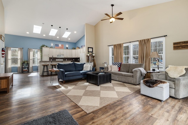 living room with a skylight, high vaulted ceiling, and light wood-type flooring