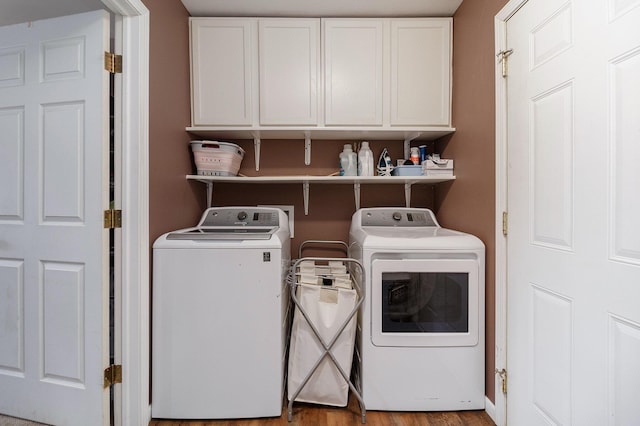 washroom featuring separate washer and dryer, wood-type flooring, and cabinets