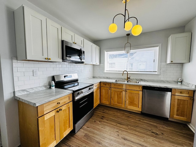 kitchen featuring sink, stainless steel appliances, dark hardwood / wood-style floors, white cabinets, and decorative light fixtures