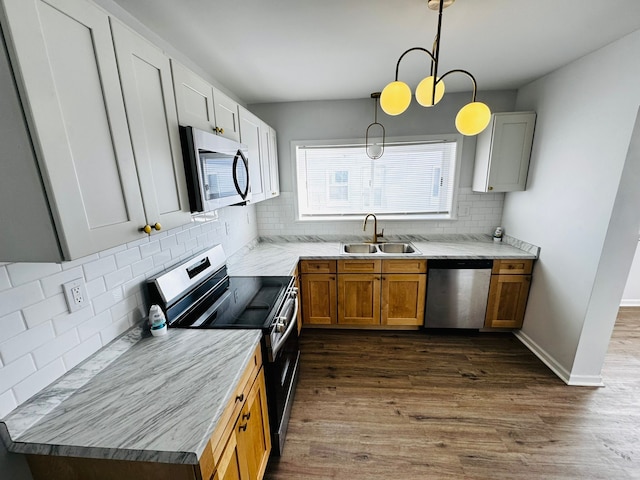 kitchen featuring sink, appliances with stainless steel finishes, hanging light fixtures, dark hardwood / wood-style flooring, and decorative backsplash