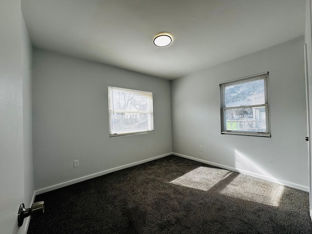 unfurnished room featuring dark colored carpet