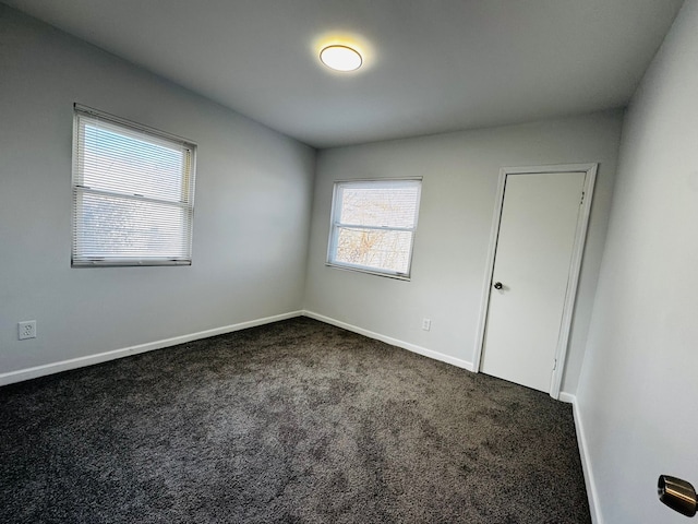 unfurnished room with dark colored carpet