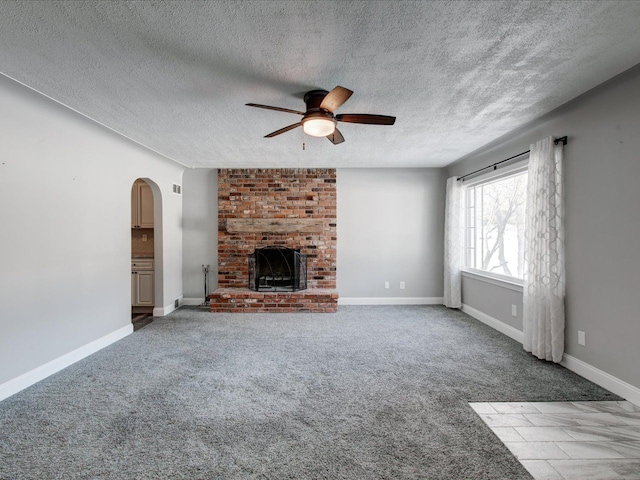 unfurnished living room with ceiling fan, carpet flooring, a textured ceiling, and a fireplace