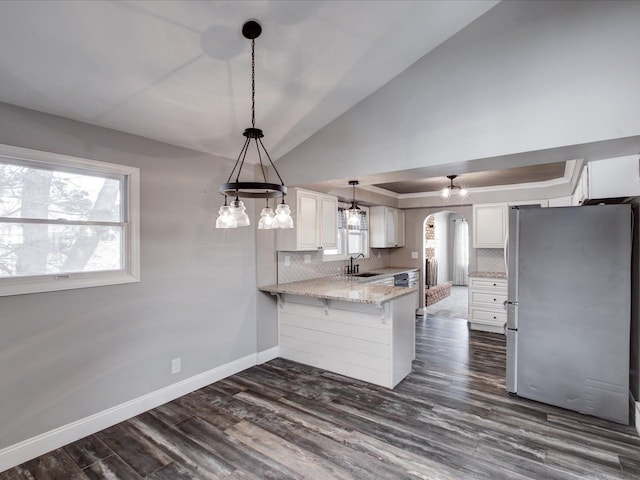 kitchen featuring stainless steel refrigerator, white cabinetry, backsplash, kitchen peninsula, and dark wood-type flooring